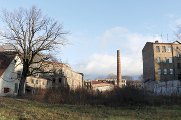 Fototapeta na wymiar Abandoned factory outdoors at sunny autumn day with brown brick walls and chimney against blue sky background