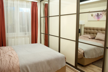 Element of a bright bedroom with a large bed and a mirror.