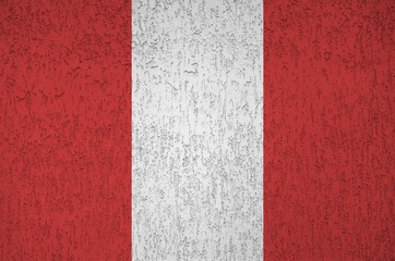 Peru flag depicted in bright paint colors on old relief plastering wall. Textured banner on rough...