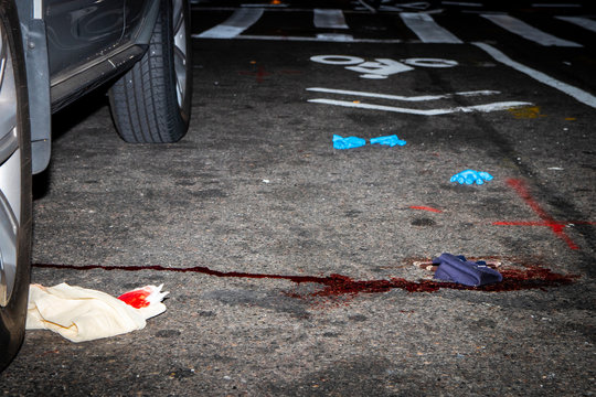Blood stains on the street in New York City, next to discarded latex gloves and blood soaked rags
