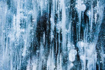 Blue ice with air bubbles in the frozen lake. Macro image. Winter nature background