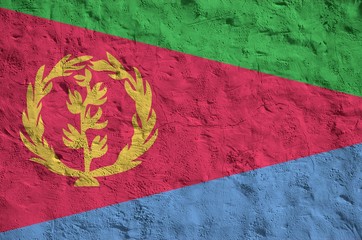 Eritrea flag depicted in bright paint colors on old relief plastering wall. Textured banner on...