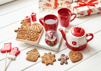 Christmas cookies and mug of hot tea, christmas time. Christmas gingerbread, candy, coffee in red cup on wooden table on frosty winter day window background. Home cozy holidays. Postcard Template.