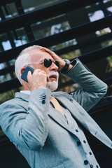 Worried senior businessman receiving bad news from business partners, holding his head