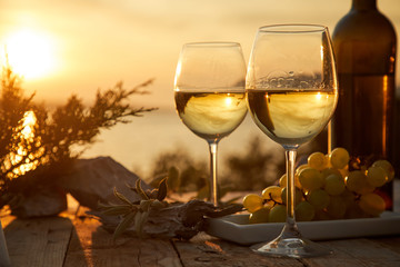 two glasses with wine during sunset time - obrazy, fototapety, plakaty