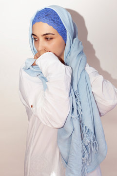 Elegant Muslim woman in white shirt and bright blue hijab. Stylish Iranian girl in Muslim clothing. Isolated portrait of attractive middle-eastern woman
