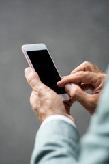 Hands holding smart phone with blank screen isolated on blurry background.