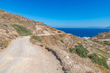 Road to Firopotamos beach with church, houses and cliffs