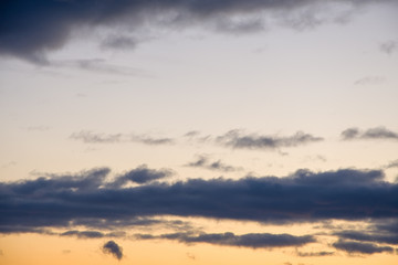 Fototapeta na wymiar Evening dark clouds against the setting sun, yellow reflections on the horizon.