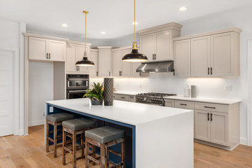 Beautiful kitchen in new luxury home with waterfall island, quartz counter tops, farmhouse sink, and hardwood floors.