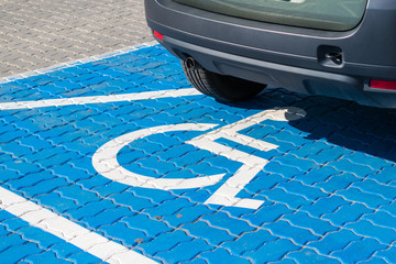 Vehicle on a fresh blue painted parking spot for people with functional impairment.  Social...