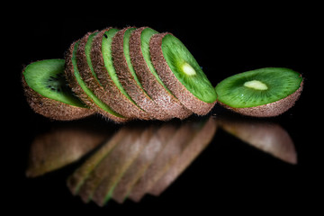 Fresh organic kiwi, sliced, with reflection on shiny black background