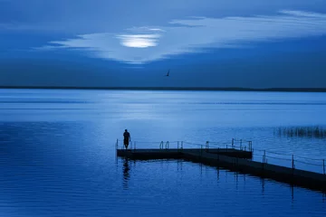 Mann auf Pontonpier in blauer Nacht. Farbe des Jahres 2020 Pantone Classic Blue © Maya Kruchancova