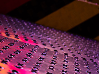 Fototapeta premium Close up of the ribbed non slip steel floor plates, reflecting different colours.