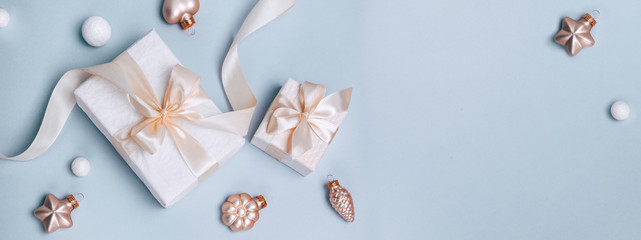 Christmas holiday composition, white gift boxes and golden Christmas toys on a light blue background. Minimalism, flat lay. Copy space