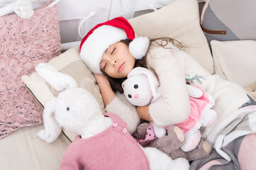 Fototapeta premium Magical morning. Christmas eve concept. Sweet home. Girl little kid relaxing on bed light interior with christmas decorations. Cozy room. Small child relaxing in bedroom. Kid lay in bed relaxing