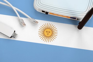 Argentina flag depicted on table with internet rj45 cable, wireless usb wifi adapter and router. Internet connection concept
