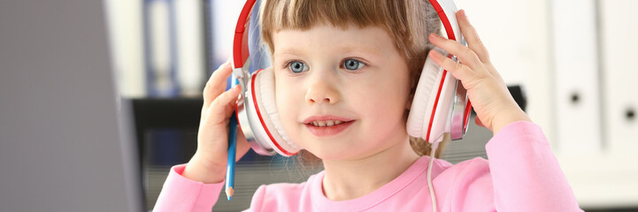 Little girl wearing headphones use mobile computer
