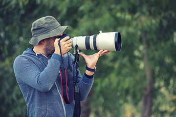 Professional nature and wildlife photographer outdoor hand holding camera with big pro lens taking pictures