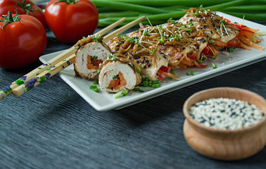 Rolls with fresh chicken breast with greens, carrot slices, bell peppers on a dark cutting board. The concept of healthy homemade food. Dark wooden background.