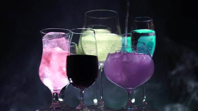 Close up view of different shape glasses with night club drinks on dark foggy background. New Year or Christmas celebration alcohol, cocktails  poured by barman or waiter.