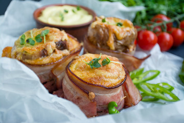 Baked young potatoes with cheese, bacon. Dark background. Close-up.