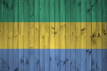 Gabon flag depicted in bright paint colors on old wooden wall. Textured banner on rough background