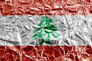 Lebanon flag depicted in paint colors on shiny crumpled aluminium foil closeup. Textured banner on...