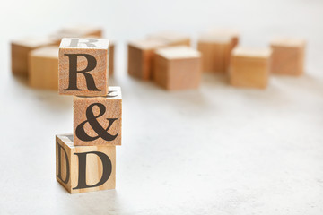 Three wooden cubes with letters R&D (means Research & Development ), on white table, more in...