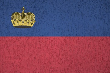 Liechtenstein flag depicted in bright paint colors on old relief plastering wall. Textured banner...