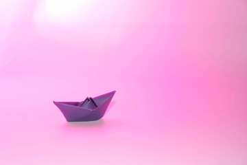 Paper blue ship in the imaginary sea of Magenta Purple Color. Copy space.