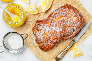 Homemade freshly baked braided (Wicker) pie with lemon jam and powdered sugar. Fresh  citrus pastries for tea and coffee. Selective focus