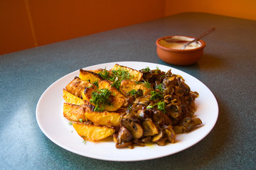 Grilled potatoes with fried mushrooms.Served in white plate. Selective focus.