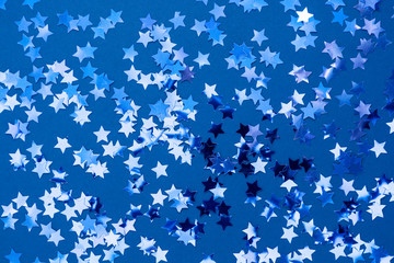 Blue abstract Christmas background or texture with stars confetti on blue background.