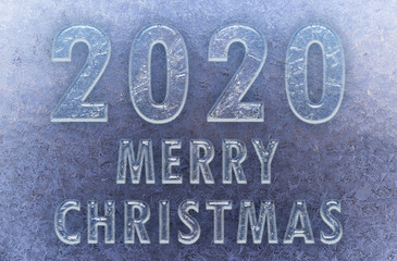 Texture of snowflakes on transparent glass. Inscription 2020 merry christmas. Beautiful frosty pattern on the window. Winter wallpaper frosty snowflakes on the glass.