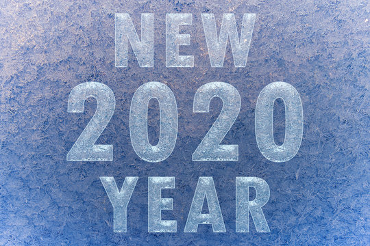 Texture of snowflakes on transparent glass. Inscription 2020 new year. Beautiful frosty pattern on the window. Winter wallpaper frosty snowflakes on the glass.