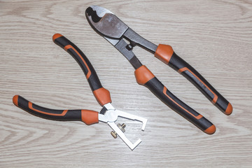 Professional electrician wire cutters and wire stripper on wooden background