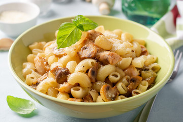 Pasta with chicken, mushrooms and parmesan cheese on concrete background. Selective focus.