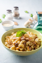 Pasta with chicken, mushrooms and parmesan cheese on concrete background. Selective focus.