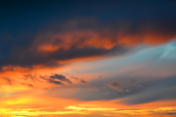 Fototapeta premium Ciemne burzowe chmury na złotym niebie podczas zachodu słońca. Poświata zachodzącego słońca. Scenic sundown cloudscape na tle.