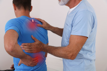 Man with back pain. Chiropractic pain relief therapy. Spine physical therapist and paient.