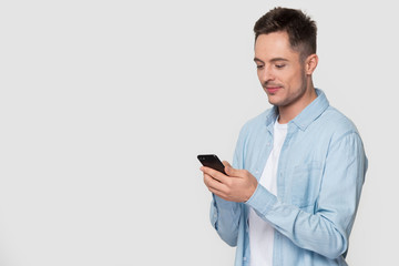 Young man interested looking at smartphone typing message chatting online
