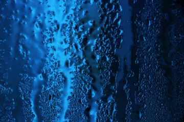 Winter background with frozen water on the window. Trend color of 2020 - Classic Blue © zsnk