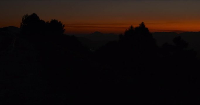 Pan left to right, Scenic shot of silhouette trees and mountains at sunset near Marbella, Spain.
