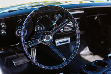 close up and selective focus on antique car black leather steering wheel, simple old style interior, and Dashboard Counters background