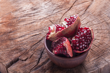 sliced pomegranate in a clay plate on a wooden background