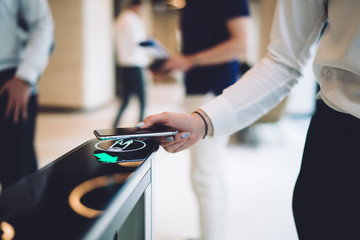Stylish woman walking through electronic turnstile