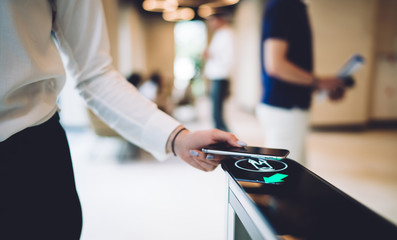 Woman going through electronic turnstile with mobile