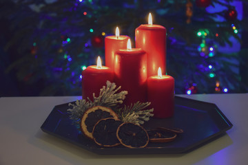 Świąteczne zapalone świece na tle choinki i dekoracji świątecznych.