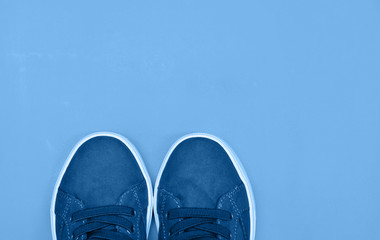Sporty shoes in trendy blue color background.